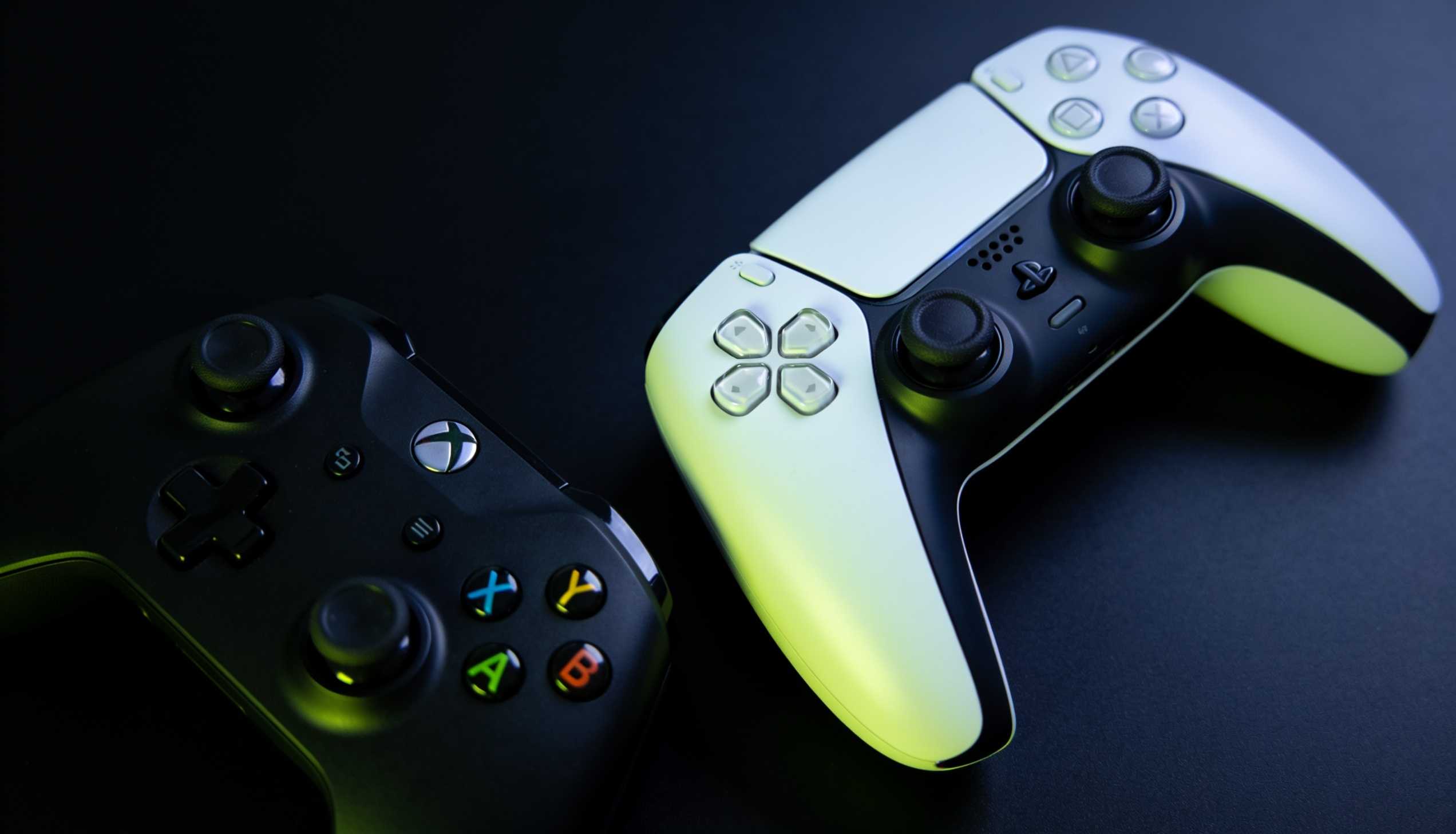 PlayStation DualSense and Xbox wireless controller side by side on a dark surface